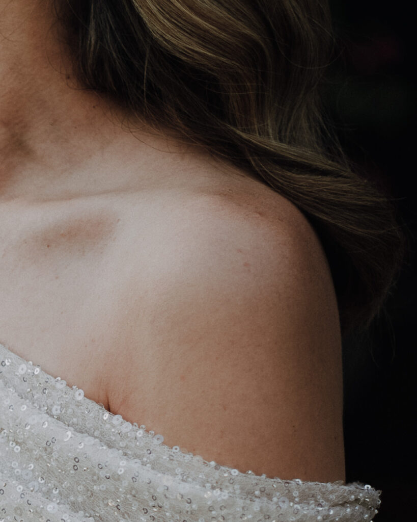 Elegant bridal portrait detail showing the bride's shoulder and wedding dress captured in soft natural light in the mediterranean.